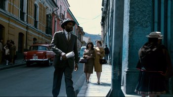 Movie still from “Che: Part Two” (2008), directed by Steven Soderbergh – A man wearing a suit and hat walking down a street; Wide shot, Low angle
