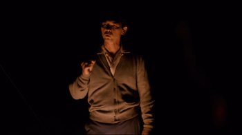 Movie still from “Che: Part Two” (2008), directed by Steven Soderbergh – A man standing in the dark smoking a cigarette; Medium shot, Low angle