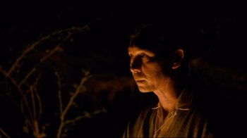 Movie still from “Che: Part Two” (2008), directed by Steven Soderbergh – A man is standing in the dark with his head turned to the side; Close Up shot, Low angle