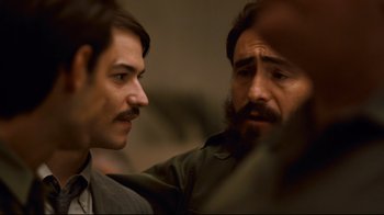 Movie still from “Che: Part Two” (2008), directed by Steven Soderbergh – A man with a beard and mustache and a man with a beard and mustache; Close Up shot, Over the shoulder angle