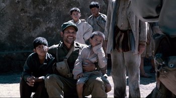 Movie still from “Che: Part Two” (2008), directed by Steven Soderbergh – A group of men and boys sitting next to each other; Medium shot, High angle