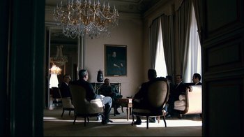 Movie still from “Che: Part Two” (2008), directed by Steven Soderbergh – A group of people sitting around a room; Wide shot, Low angle