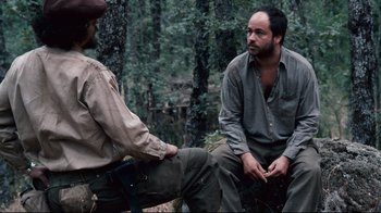 Movie still from “Che: Part Two” (2008), directed by Steven Soderbergh – Two men sitting on a bench in the woods; Medium shot, Over the shoulder angle