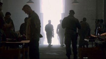 Movie still from “Che: Part Two” (2008), directed by Steven Soderbergh – A group of people walking in a room with light coming through the window; Wide shot, Over the shoulder angle