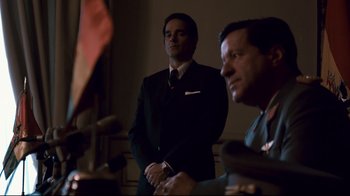 Movie still from “Che: Part Two” (2008), directed by Steven Soderbergh – A man in a suit and tie standing next to another man in a suit and tie; Medium shot, Low angle