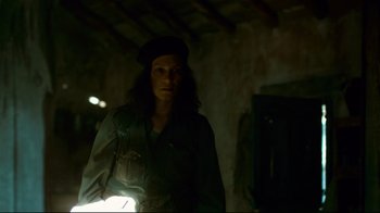 Movie still from “Che: Part Two” (2008), directed by Steven Soderbergh – A woman standing in the dark with a flashlight in her hand; Medium shot, Low angle