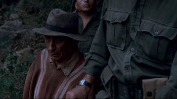 Movie still from “Che: Part Two” (2008), directed by Steven Soderbergh – An older man wearing a hat and a watch; Medium shot, High angle