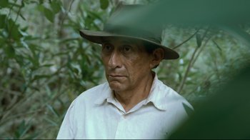 Movie still from “Che: Part Two” (2008), directed by Steven Soderbergh – A man wearing a hat standing next to a tree; Close Up shot, High angle