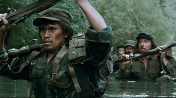 Movie still from “Che: Part Two” (2008), directed by Steven Soderbergh – A group of people in the water with guns; Medium shot, Over the shoulder angle