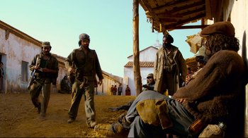 Movie still from “Che: Part Two” (2008), directed by Steven Soderbergh – A group of men standing next to each other on a dirt field; Wide shot, Low angle