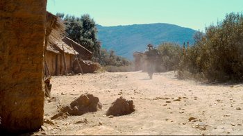 Movie still from “Che: Part Two” (2008), directed by Steven Soderbergh – A man riding a motorcycle down a dirt road; Extreme Wide shot, High angle