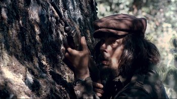 Movie still from “Che: Part Two” (2008), directed by Steven Soderbergh – A man with a beard and a hat is holding a rifle; Close Up shot, Low angle