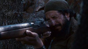 Movie still from “Che: Part Two” (2008), directed by Steven Soderbergh – A man with a beard is holding a rifle; Close Up shot, Low angle