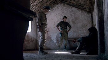 Movie still from “Che: Part Two” (2008), directed by Steven Soderbergh – A couple of men standing next to each other in a room; Wide shot, Over the shoulder angle