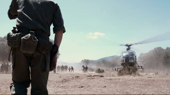 Movie still from “Che: Part Two” (2008), directed by Steven Soderbergh – A group of people standing in the dirt near a helicopter; Wide shot, Low angle