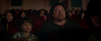 Movie still from “Chef” (2014), directed by Jon Favreau – A man and a boy watching a movie in a theater; Medium shot, Over the shoulder angle
