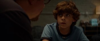 Movie still from “Chef” (2014), directed by Jon Favreau – A young boy looking at the camera while a man looks on; Close Up shot, Over the shoulder angle