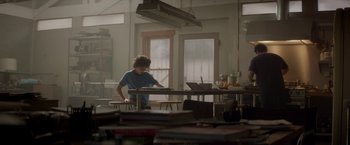 Movie still from “Chef” (2014), directed by Jon Favreau – A person standing at a table with a laptop; Wide shot, Low angle