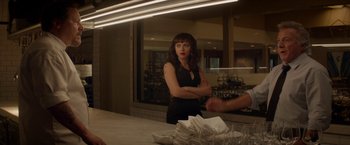 Movie still from “Chef” (2014), directed by Jon Favreau – A woman standing in front of a counter with folded napkins on the counter; Medium shot, Over the shoulder angle