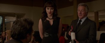 Movie still from “Chef” (2014), directed by Jon Favreau – A woman in a black dress standing next to a bottle of wine; Medium shot, Over the shoulder angle