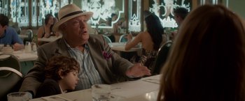 Movie still from “Chef” (2014), directed by Jon Favreau – An older man sitting at a table with a young boy; Medium shot, Over the shoulder angle