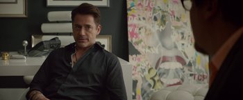 Movie still from “Chef” (2014), directed by Jon Favreau – A person sitting in a chair near a painting; Close Up shot, Over the shoulder angle