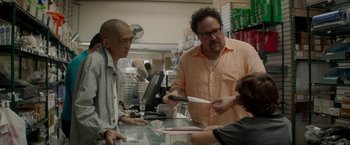 Movie still from “Chef” (2014), directed by Jon Favreau – A man in an orange shirt is handing a knife to another man in an orange shirt; Medium shot, Over the shoulder angle