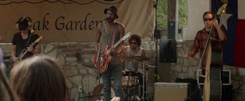 Movie still from “Chef” (2014), directed by Jon Favreau – A man with a hat on playing a guitar and another man with a drum; Medium shot, Over the shoulder angle