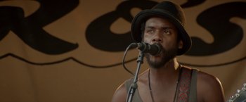 Movie still from “Chef” (2014), directed by Jon Favreau – A man with a hat is singing into a microphone; Close Up shot, Low angle