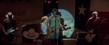 Movie still from “Chef” (2014), directed by Jon Favreau – A man with a hat on playing a guitar and another man with a guitar; Wide shot, Over the shoulder angle