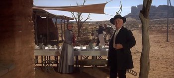 Movie still from “Cheyenne Autumn” (1964), directed by John Ford – A man and a woman standing in front of a table; Wide shot, Low angle