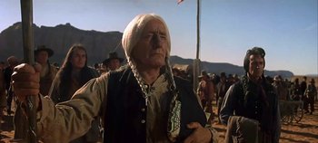 Movie still from “Cheyenne Autumn” (1964), directed by John Ford – An old man with long white hair is standing in the desert; Medium shot, Low angle