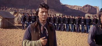 Movie still from “Cheyenne Autumn” (1964), directed by John Ford – A group of men standing next to each other on a beach; Medium shot, Over the shoulder angle
