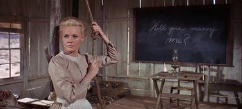 Movie still from “Cheyenne Autumn” (1964), directed by John Ford – A woman holding a rope in a room with chalkboards; Medium shot, Low angle