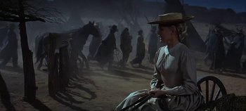 Movie still from “Cheyenne Autumn” (1964), directed by John Ford – A woman sitting in a dirt field next to a horse; Medium shot, Low angle