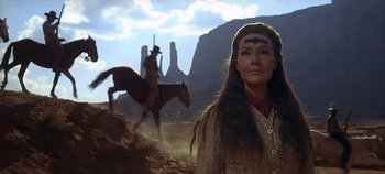 Movie still from “Cheyenne Autumn” (1964), directed by John Ford – A woman standing next to a man on a horse in the desert; Close Up shot, Low angle