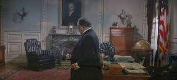 A man in a suit standing in front of a fireplace