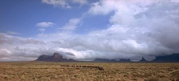 Movie still from “Cheyenne Autumn” (1964), directed by John Ford – A herd of wild animals walking across a dry grass field; Extreme Wide shot, Low angle