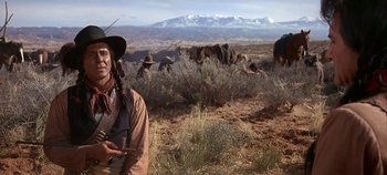 Movie still from “Cheyenne Autumn” (1964), directed by John Ford – A man in a cowboy hat standing next to a herd of cattle; Medium shot, Low angle