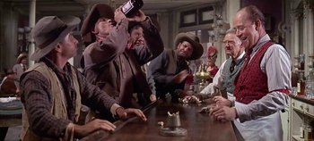 Movie still from “Cheyenne Autumn” (1964), directed by John Ford – A group of men sitting around a table drinking; Wide shot, Low angle