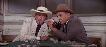 Movie still from “Cheyenne Autumn” (1964), directed by John Ford – Two men sitting at a poker table with cards and a cigar; Medium shot, Low angle