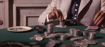 Movie still from “Cheyenne Autumn” (1964), directed by John Ford – A man is playing a game of poker with a bunch of coins; Extreme Close Up shot, High angle
