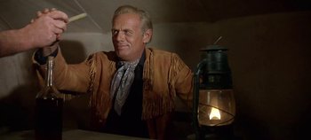 Movie still from “Cheyenne Autumn” (1964), directed by John Ford – A man in a cowboy outfit sitting in front of a lantern; Medium shot, Low angle