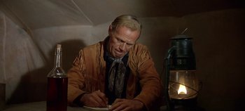 Movie still from “Cheyenne Autumn” (1964), directed by John Ford – A man sitting at a table writing on a piece of paper; Medium shot, Low angle