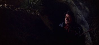 Movie still from “Cheyenne Autumn” (1964), directed by John Ford – A man sitting in the dark next to a plant; Medium shot, Low angle