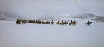 Movie still from “Cheyenne Autumn” (1964), directed by John Ford – A group of people riding horses across a snow covered field; Extreme Wide shot, High angle