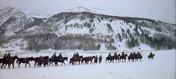 Movie still from “Cheyenne Autumn” (1964), directed by John Ford – A group of people riding horses across a snow covered field; Extreme Wide shot, High angle