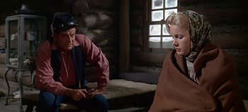 Movie still from “Cheyenne Autumn” (1964), directed by John Ford – A man and a woman sitting on a bench in front of a window; Medium shot, Over the shoulder angle
