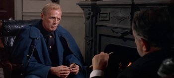 Movie still from “Cheyenne Autumn” (1964), directed by John Ford – A man sitting in front of a fireplace holding a cigarette; Medium shot, Over the shoulder angle