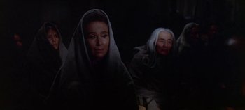 Movie still from “Cheyenne Autumn” (1964), directed by John Ford – Two women in a dimly - lit room , one of whom has a blanket over her head; Medium shot, Over the shoulder angle